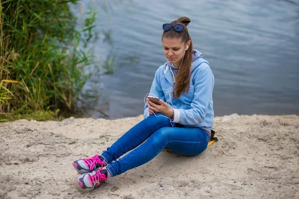 Genç gülümseyen kadın mükemmel ruhları ile bir telefon ve müzik dinler