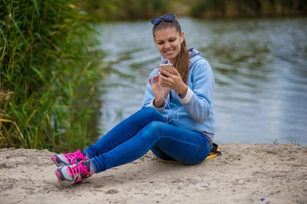 Mükemmel ruhları bir telefon ile genç gülümseyen kadın müzik dinliyor