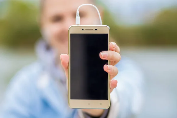 Young smiling woman in excellent spirits with a phone listens to music — Stock Photo, Image