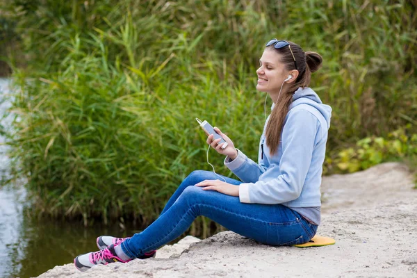 Mükemmel ruhları bir telefon ile genç gülümseyen kadın müzik dinliyor