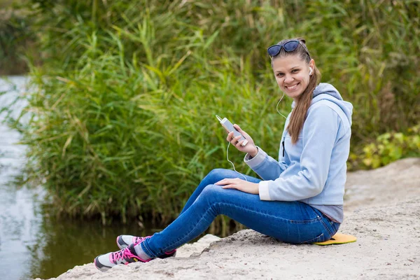 Mükemmel ruhları bir telefon ile genç gülümseyen kadın müzik dinliyor