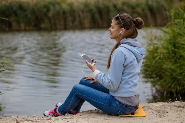 Joven mujer sonriente de excelente ánimo con un teléfono escucha música — Foto de Stock