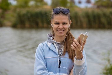 Mükemmel ruhları bir telefon ile genç gülümseyen kadın müzik dinliyor