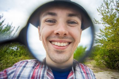 Büyüteç bir şapka komik bir yüz ile neşeli bir adam tutar