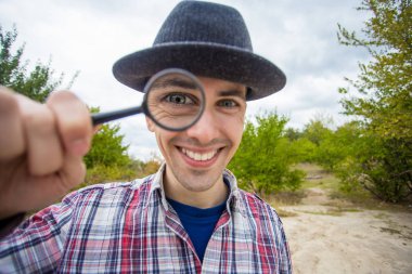 Komik bir surat ile neşeli bir adam bir Büyüteç Camı tutan