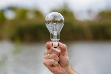Ampul elektrik doğa arka planda tutan erkekler el