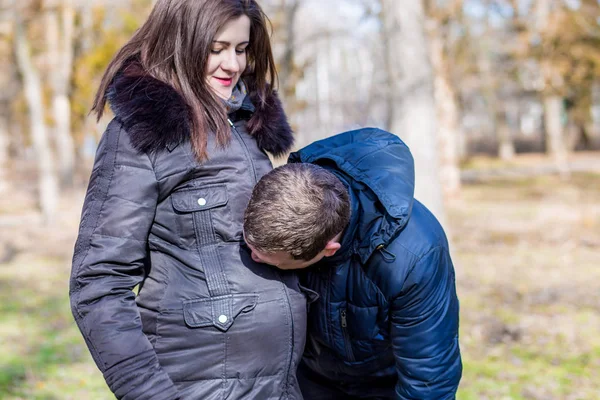 Um homem beija a barriga de sua bela esposa grávida — Fotografia de Stock
