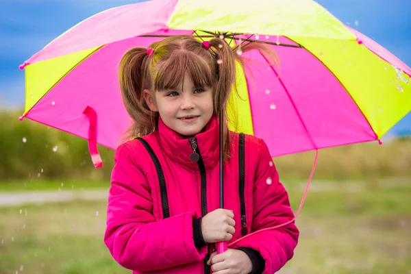 Divertente ragazza carina con ombrello colorato che gioca in giardino — Foto Stock