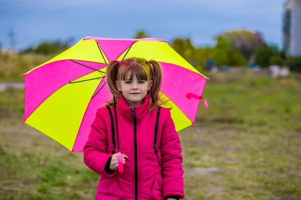 Vicces, aranyos lány színes esernyő a kertben játszik — Stock Fotó