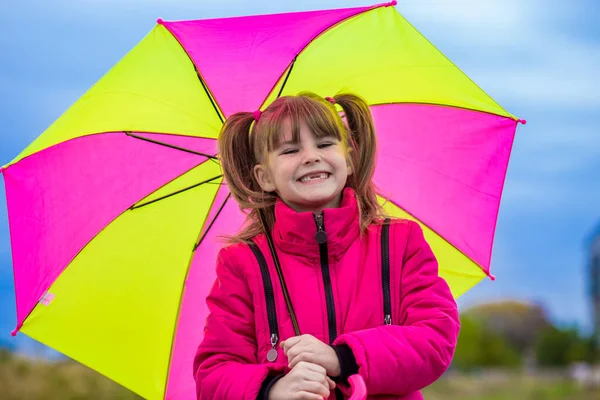 Vicces, aranyos lány színes esernyő a kertben játszik — Stock Fotó