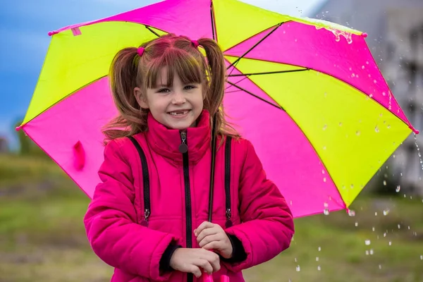 Bambino felice ragazza ridendo con un ombrello sotto la pioggia — Foto Stock