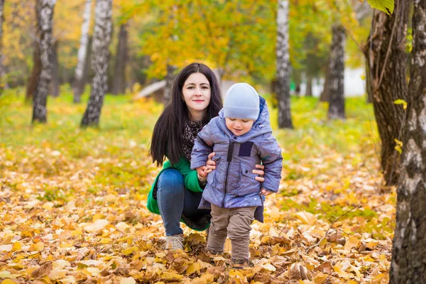 Μητέρα με το μικρό του γιο που βρίσκεται στο πάρκο σε φόντο φθινοπωρινά φύλλα — Φωτογραφία Αρχείου