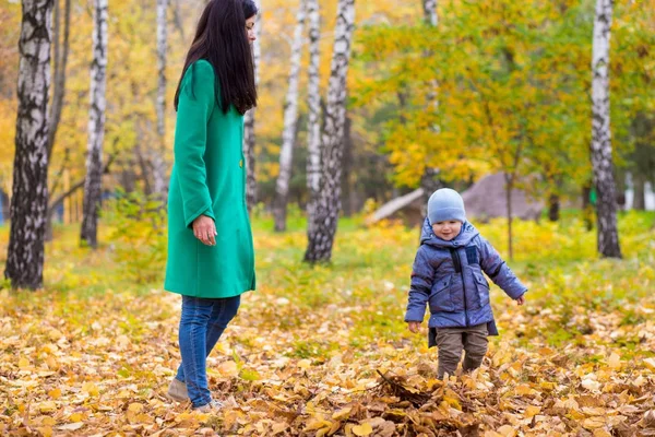 Μητέρα με το μικρό του γιο που βρίσκεται στο πάρκο σε φόντο φθινοπωρινά φύλλα — Φωτογραφία Αρχείου