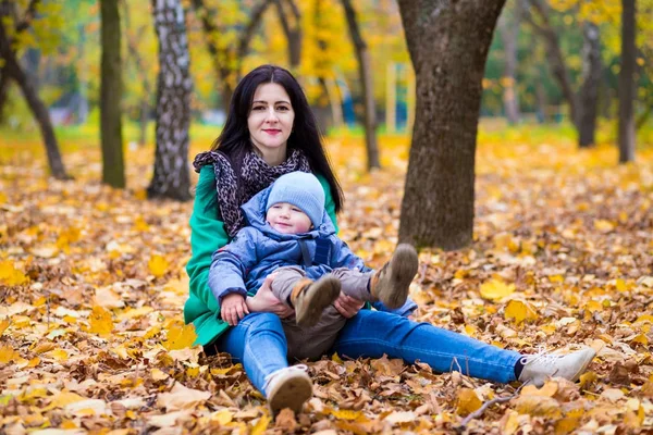 Мать с маленьким сыном играет в осеннем парке — стоковое фото