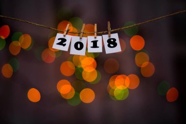 Mutlu yeni yıl 2018 metinle garland bokeh arka plan üzerinde kağıtlara clothespins ile