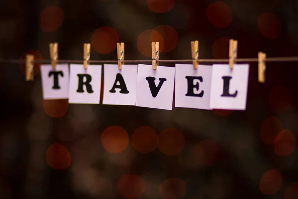 Travel text on papers with clothespins with garland bokeh on background — Stock Photo, Image