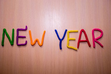 Hafif ahşap arka plan üzerinde renkli parlak hamuru dan yeni yıl mesajı. Renkli parlak yeni yıl arka plan 