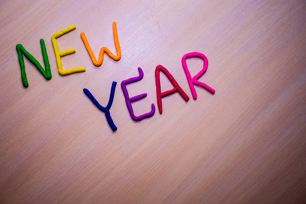 Hafif ahşap arka plan üzerinde renkli parlak hamuru dan yeni yıl mesajı. Renkli parlak yeni yıl arka plan 