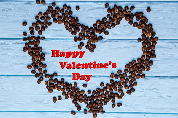 青い木製のテーブルの上のコーヒー豆からハート型に幸せなバレンタインデーの背景 — ストック写真