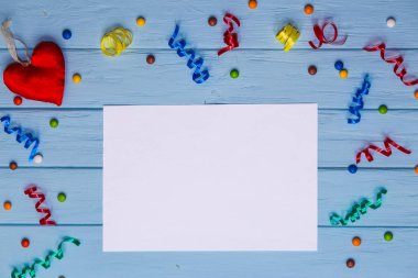 Etrafında renkli kurdeleler ve el yapımı kalp mavi ahşap masa üzerinde beyaz boş kağıt. Office kompozisyon