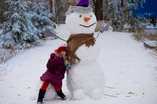 Uma Menina Alegre Senta Perto Grande Boneco Neve Realmente Engraçado — Fotografia de Stock