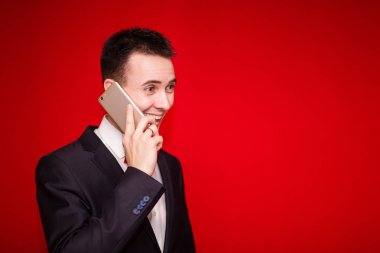 Kırmızı zemin üzerine izole cep telefonuyla konuşan genç gülmek işadamı portresi