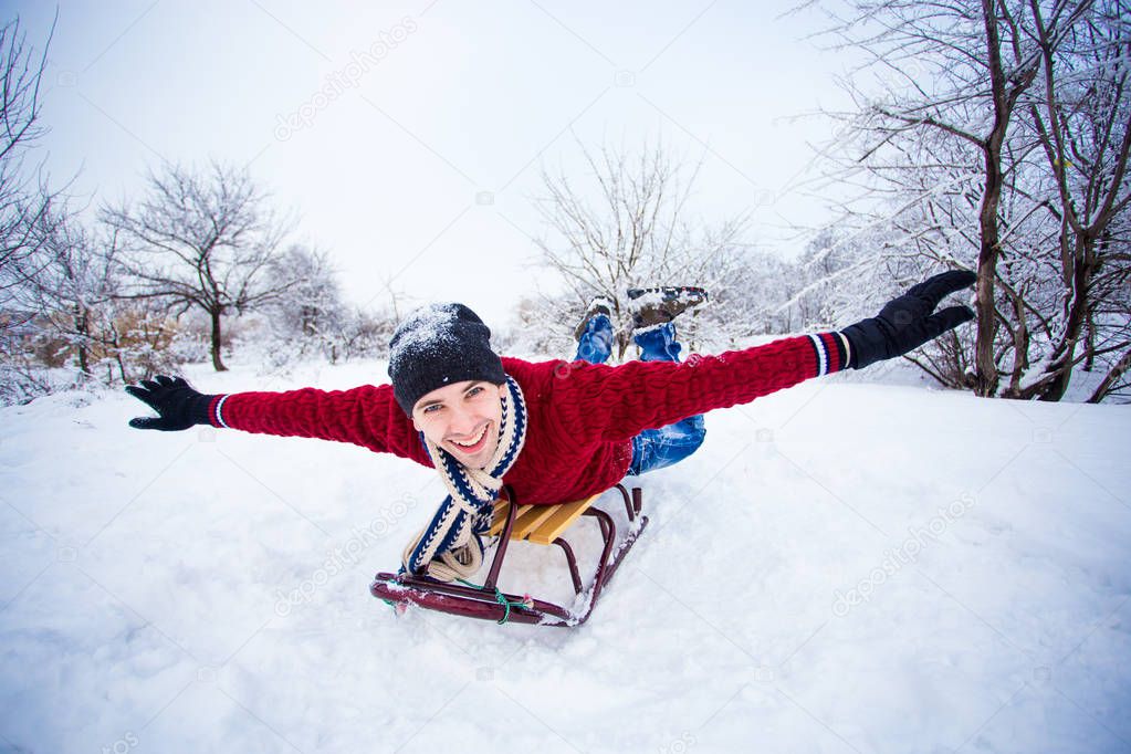 Crazy man enjoy a sleigh ride. Man sledding. Funny man play outdoors in snow. Man sled in Alps mountains in winter. Outdoor fun for Christmas vacation.