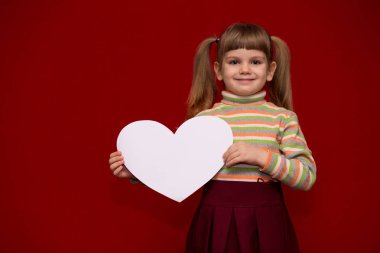Kırmızı tutun beyaz kağıt kalp üzerinde izole neşeli küçük kız portresi
