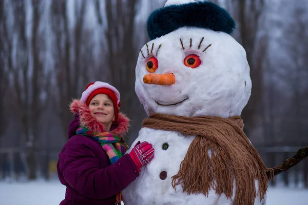 Una Piccola Ragazza Allegra Vicino Grande Pupazzo Neve Divertente Una — Foto Stock