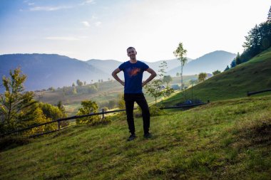 Turist adam üstünde tepe-in mavi gökyüzü ile dağlar. Keyfi güzel manzara içinde ücretsiz mutluluk adam. Seyahat kavramı