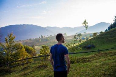 Turist adam üstünde tepe-in mavi gökyüzü ile dağlar. Keyfi güzel manzara içinde ücretsiz mutluluk adam. Seyahat kavramı