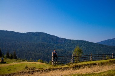 Turist adam üstünde tepe-in mavi gökyüzü ile dağlar. Keyfi güzel manzara içinde ücretsiz mutluluk adam. Seyahat kavramı