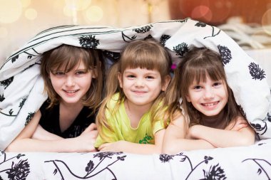 Komik little sisters battaniyenin altında gizler. Şirin kızlar yatakta eğleniyor. Çocuklar uyku, bakım veya çocukluk kavramı