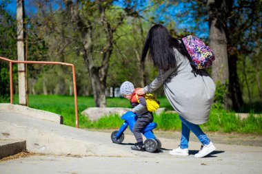 Genç anne ile küçük oğlu çocuk Motosiklet ile açık havada yürür. Etkin çocukluk
