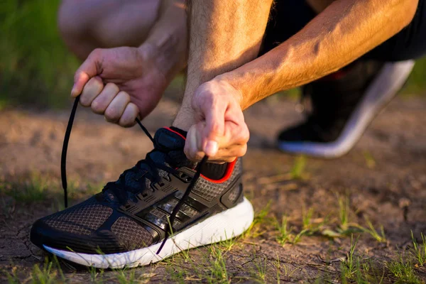 Man tying running shoes. Healthy lifestyle. Athlete tying laces for jogging on road in barefoot running shoes. Runner getting ready for training