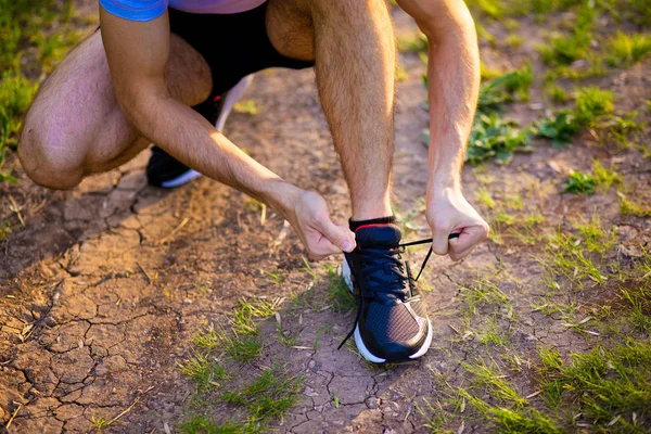 Man tying running shoes. Healthy lifestyle. Athlete tying laces for jogging on road in barefoot running shoes. Runner getting ready for training