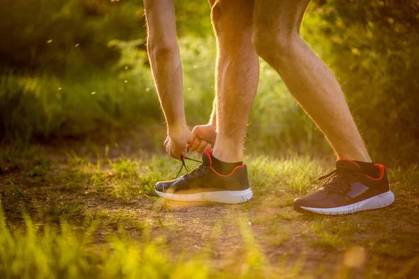 Man tying running shoes. Healthy lifestyle. Athlete tying laces for jogging on road in barefoot running shoes. Runner getting ready for training