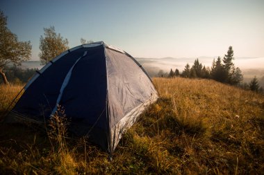 Sabah çadırı olan dağların manzarası. Ormanda kamp yapmak.