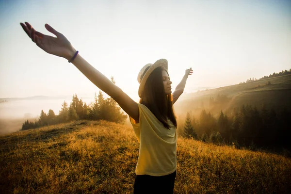 Vista laterale di giovane donna con braccia tese godendo la natura e la luce del sole in cima alla collina — Foto Stock