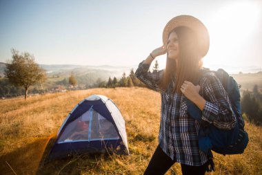 Sırt çantalı hasır şapkalı bir kadın dağlarda sonbahar ormanlarında yürüyüş yapıyor. Eğlence ve sağlıklı yaşam tarzı