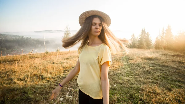 Young carefree woman enjoying nature and sunlight in straw hat
