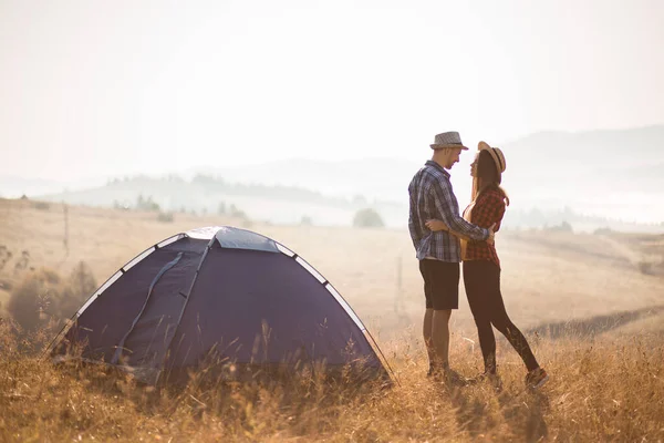 Happy tourist couple walk on top of mountains near tent and enjoy autumn morning in vacation.