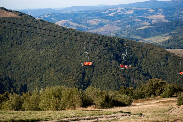 Πλευρική άποψη της κόκκινης βόλτα με το τελεφερίκ στα βουνά με όμορφη φύση φόντο. — Φωτογραφία Αρχείου