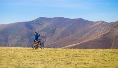 Pylypets, Ukrayna - 15 Eylül 2019: Genç parlak adam dağların zirvesinde bisiklete biniyor