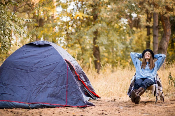 Vacaciones de camping, viajero turista mujer en suéter y sombrero negro ralaxing en tienda de campaña en el bosque, concepto de vacaciones de descanso — Foto de Stock