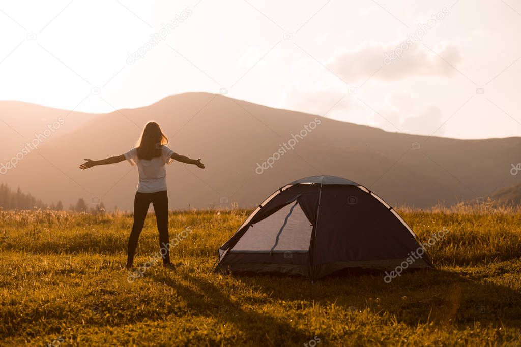 Hiker woman on top of mountain with open hands welcomes sunset