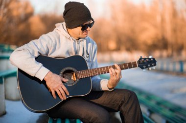 İskambil gitar ve şarkı, müzik konsepti basamaklarında oturan genç adam