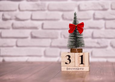 Yeni yıl. 31 Aralık. 31 Aralık ayı, takvimde küçük bir noel ağacı ve beyaz tuğla duvarda kırmızı bir fiyonk var..