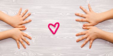 Komik afiş, tahta arka plan, çocukların elleri ve kalp sembolü.