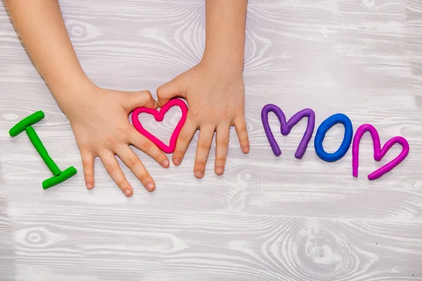 J'adore maman texte de plasticine avec des mains d'enfant sur fond blanc en bois. Joyeuse fête des mères. Fun enfants artisanat artisanal — Photo